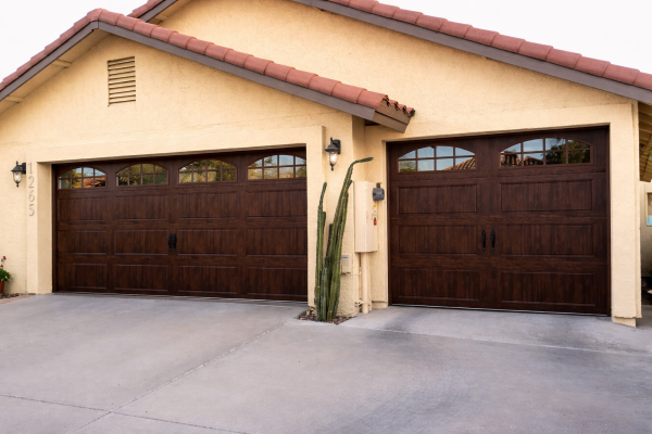 Residential home featuring dark wooden garage doors with decorative windows